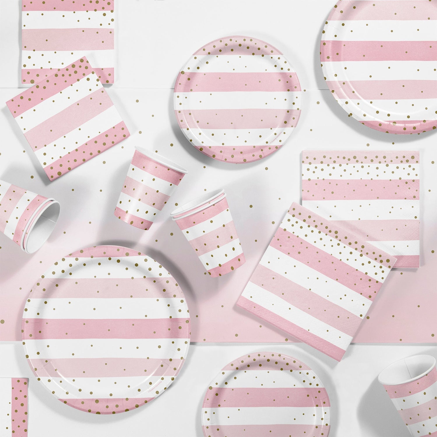 Pink and Gold Celebration Party Supplies. Pink and white striped plates, napkins and cups with gold polka dots displayed on a table