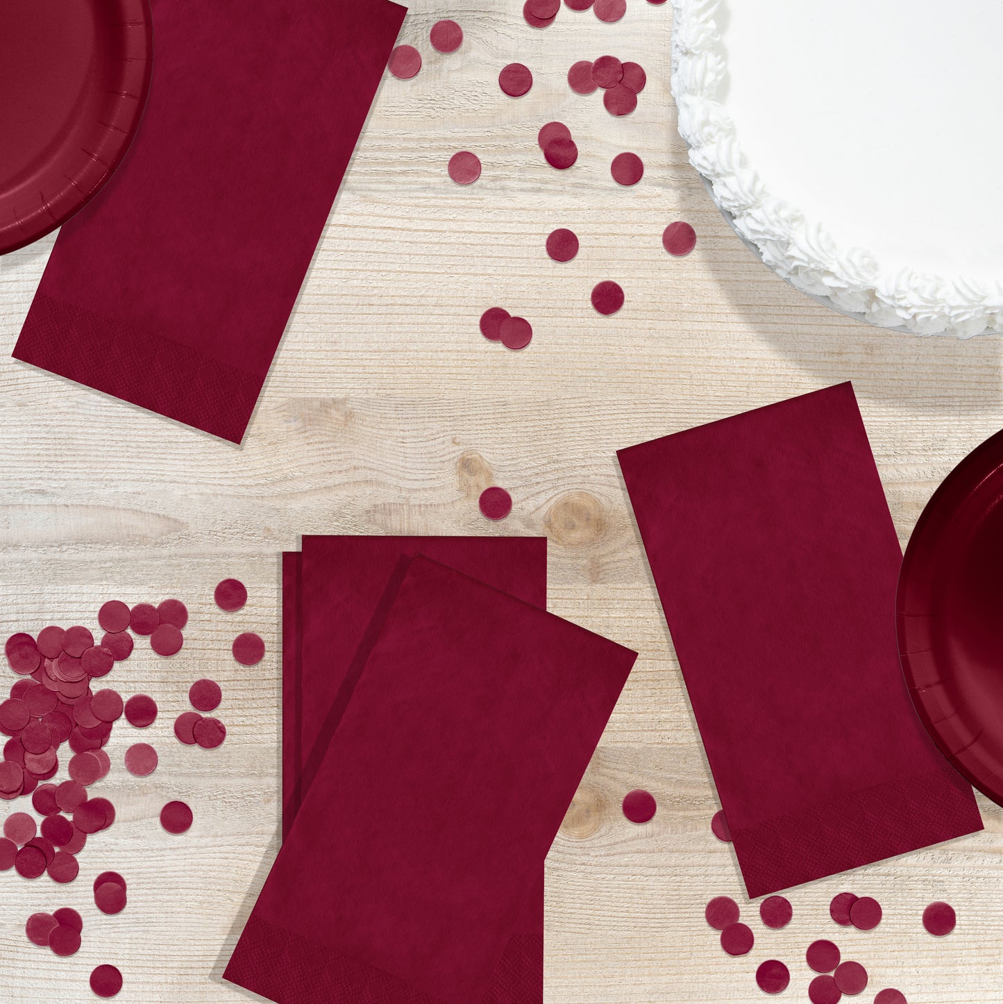 Red napkins, plates and confetti on a wooden background