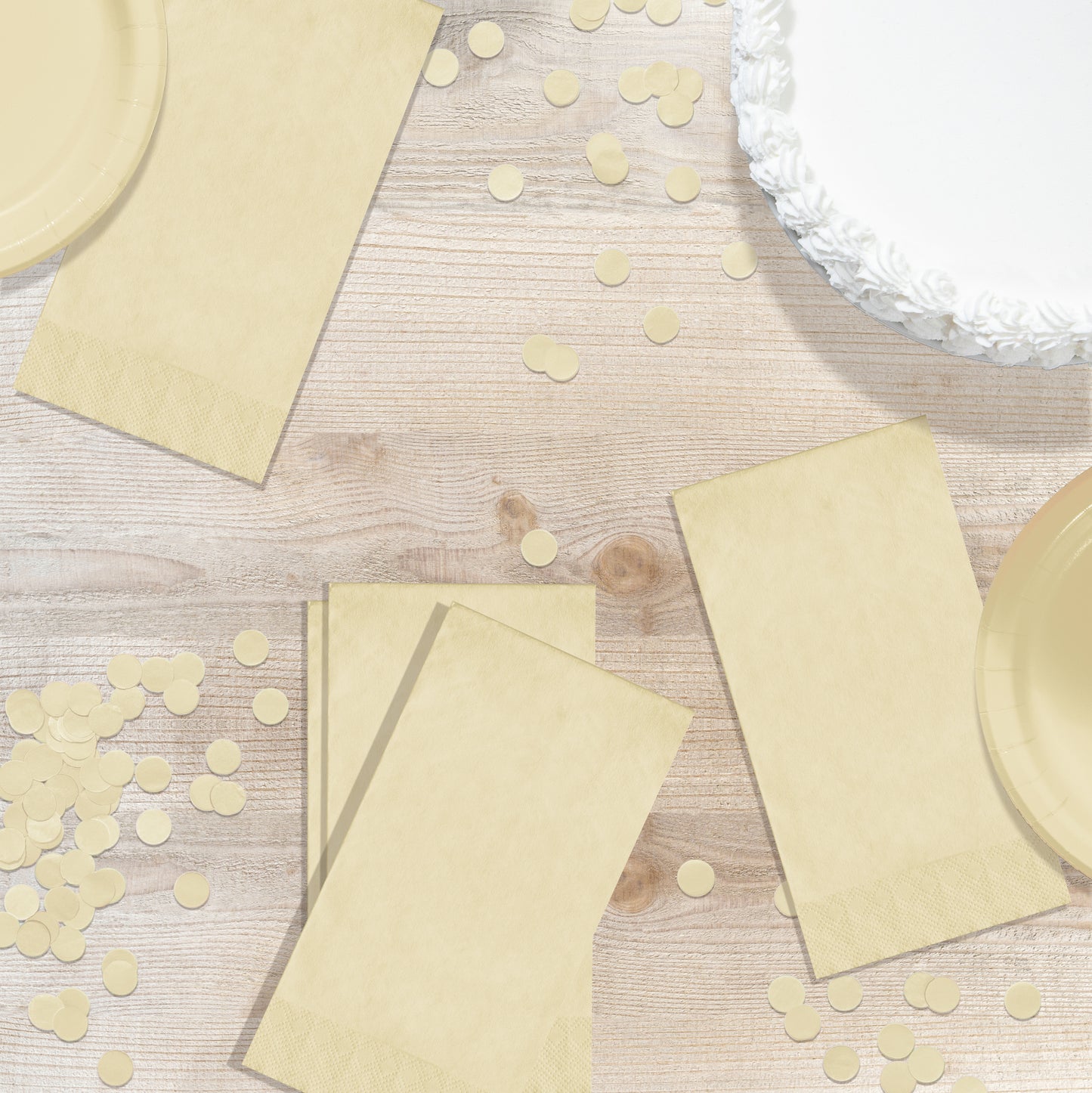 Ivory paper plates, napkins and confetti on a wooden surface