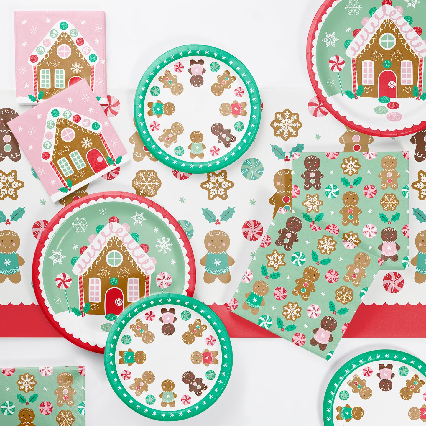 Christmas-themed paper plates and napkins with gingerbread house and candy cane designs on a white background.