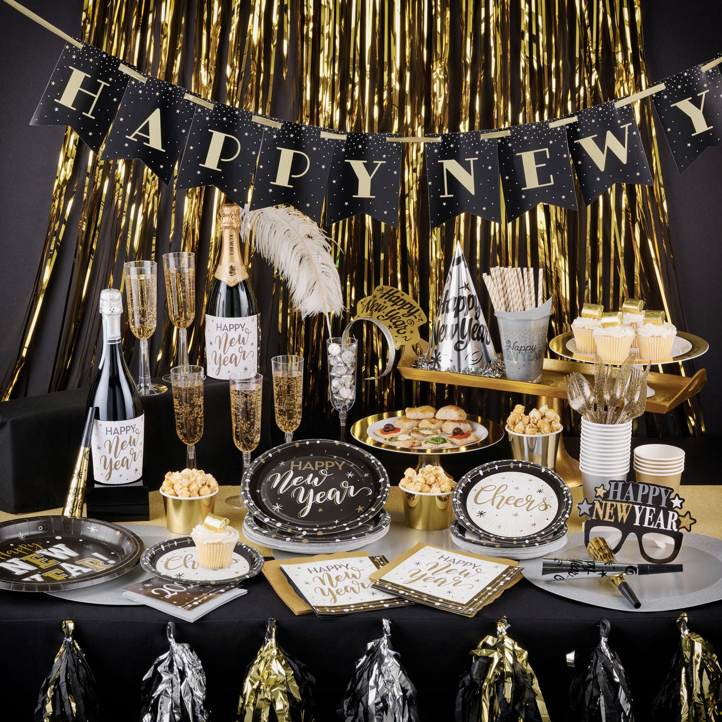 New Year's Eve party setup with table decorations, champagne, and 'Happy New Year' banner.