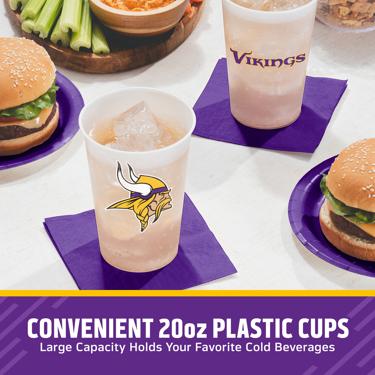Three 20oz plastic cups with Minnesota Vikings branding are shown on purple napkins in a dining setting, surrounded by burgers, celery, and bowls of food. A text banner at the bottom reads 'CONVENIENT 20oz PLASTIC CUPS Large Capacity Holds Your Favorite Cold Beverages'.