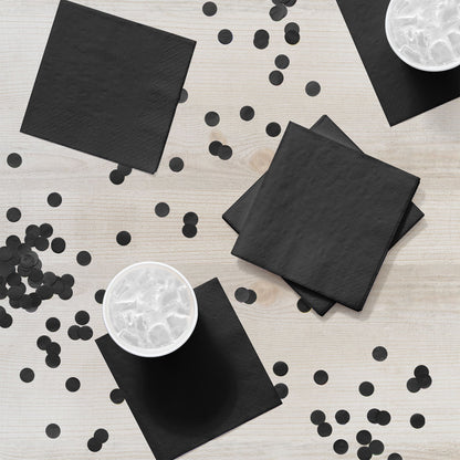 Black napkins and confetti on a light wooden surface