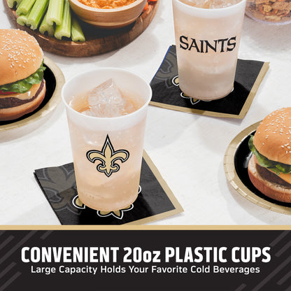 Two 20oz plastic cups with New Orleans Saints logos and 'SAINTS' text, shown on black Saints napkins with burgers and celery in a dining setting. Text at the bottom reads 'CONVENIENT 20oz PLASTIC CUPS Large Capacity Holds Your Favorite Cold Beverages'.