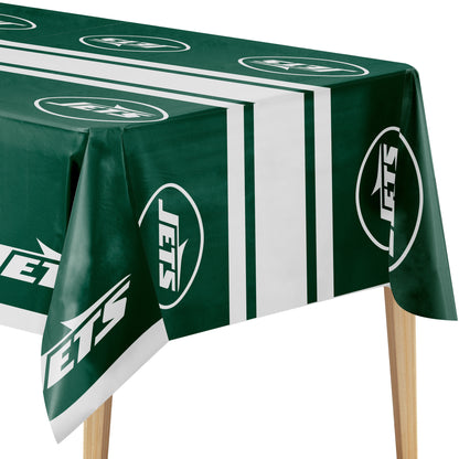 A green and white New York Jets themed tablecloth draped over a table, showing the team logo and stripes, with wooden table legs visible underneath.