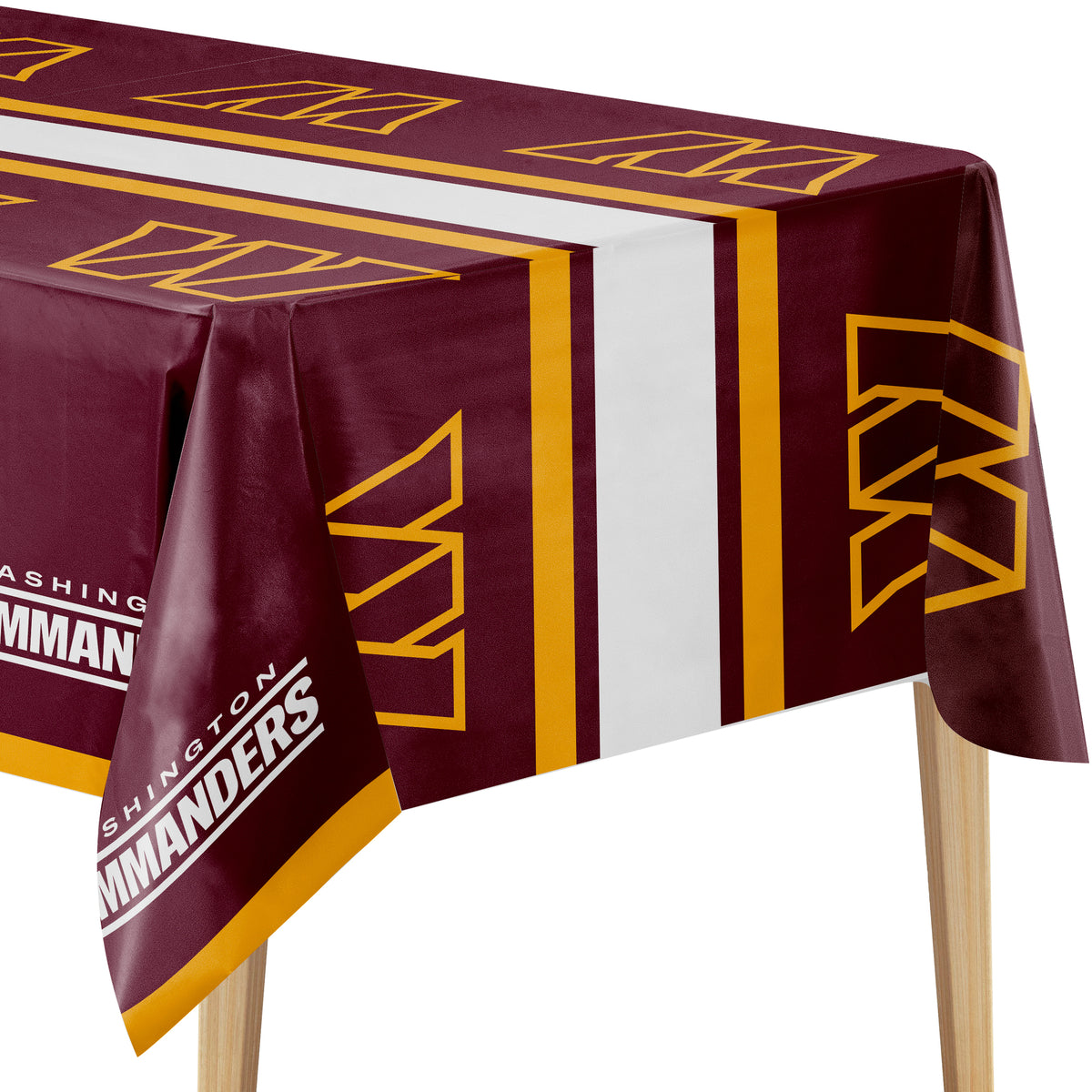 A maroon red and yellow Washington Commanders tablecloth draped over a table, featuring the team's logo and name in white text, shown against a plain white background.
