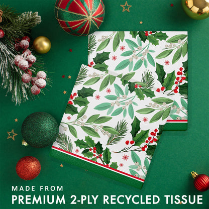 Christmas-themed paper napkins with holly design. Napkins shown on a green background with festive decorations.