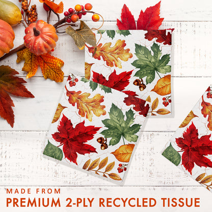 Autumn Air Beverage Napkins 192 ct. Fall-themed paper napkin with colorful leaves on a white wooden surface.