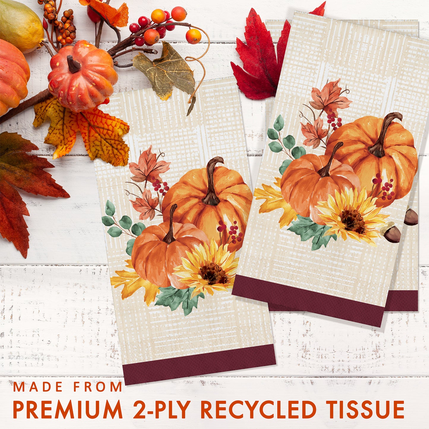Fall Feast Dinner Napkins 192 ct. Two decorative paper napkins with pumpkin and leaf designs on a white wooden surface with autumn elements.