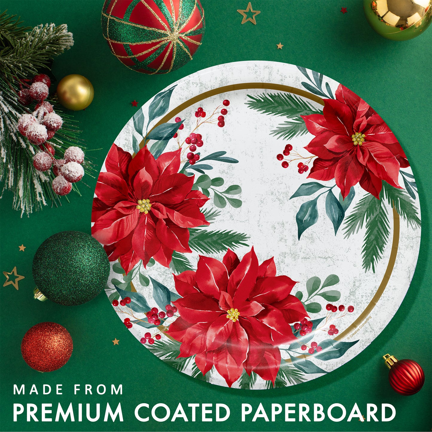 Decorative paper plate with red poinsettias and greenery on a green background with Christmas ornaments.