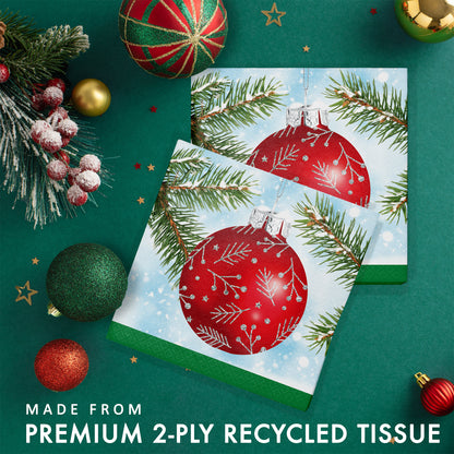 Two folded paper napkins with Christmas ornament on a green background with festive decorations.