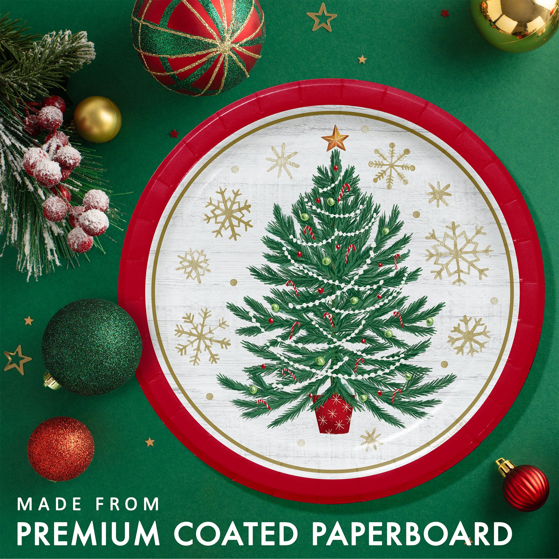 Christmas-themed paper plate with a tree design, gold snowflakes and a red rim. Plate shown on a green background with festive decorations.