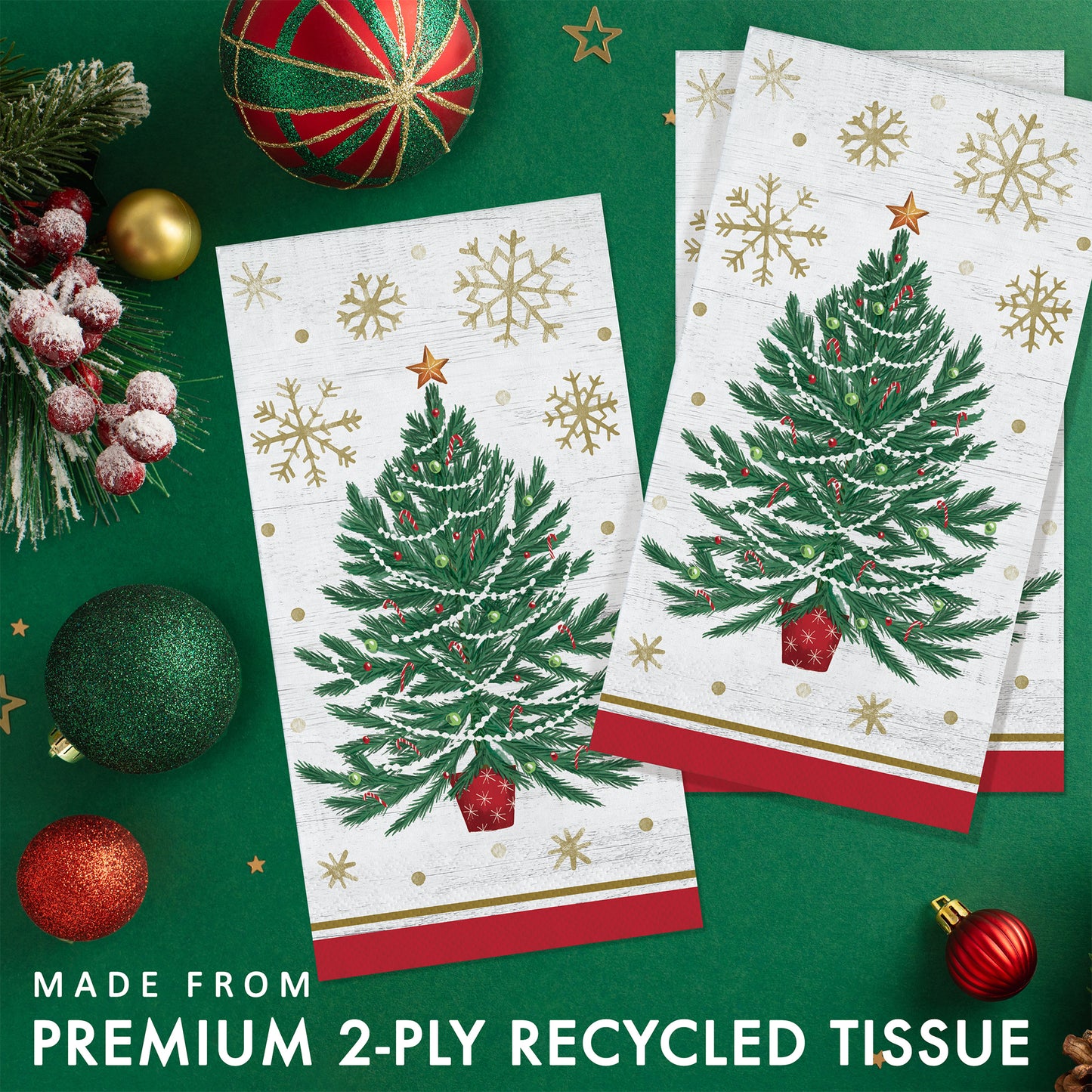 Two Christmas-themed paper napkins with tree designs and gold snowflakes. Napkins shown on a green background with festive decorations.
