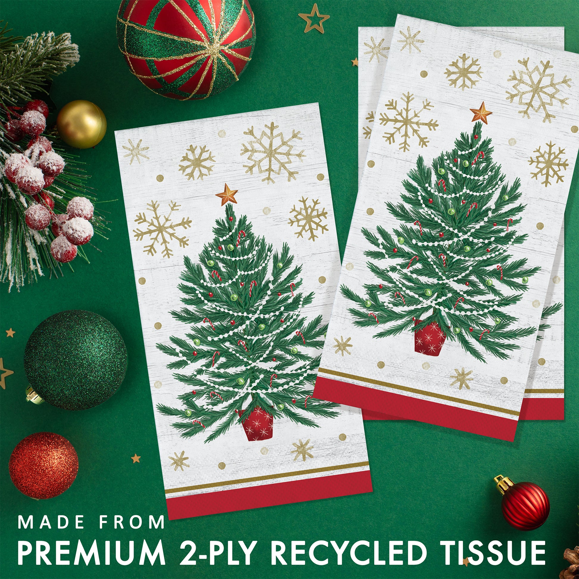 Two Christmas-themed paper napkins with tree designs and gold snowflakes. Napkins shown on a green background with festive decorations.