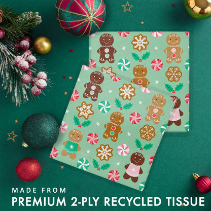 Two sets of green paper napkins with gingerbread man pattern. Napkins shown on a green background with Christmas decorations and greenery.