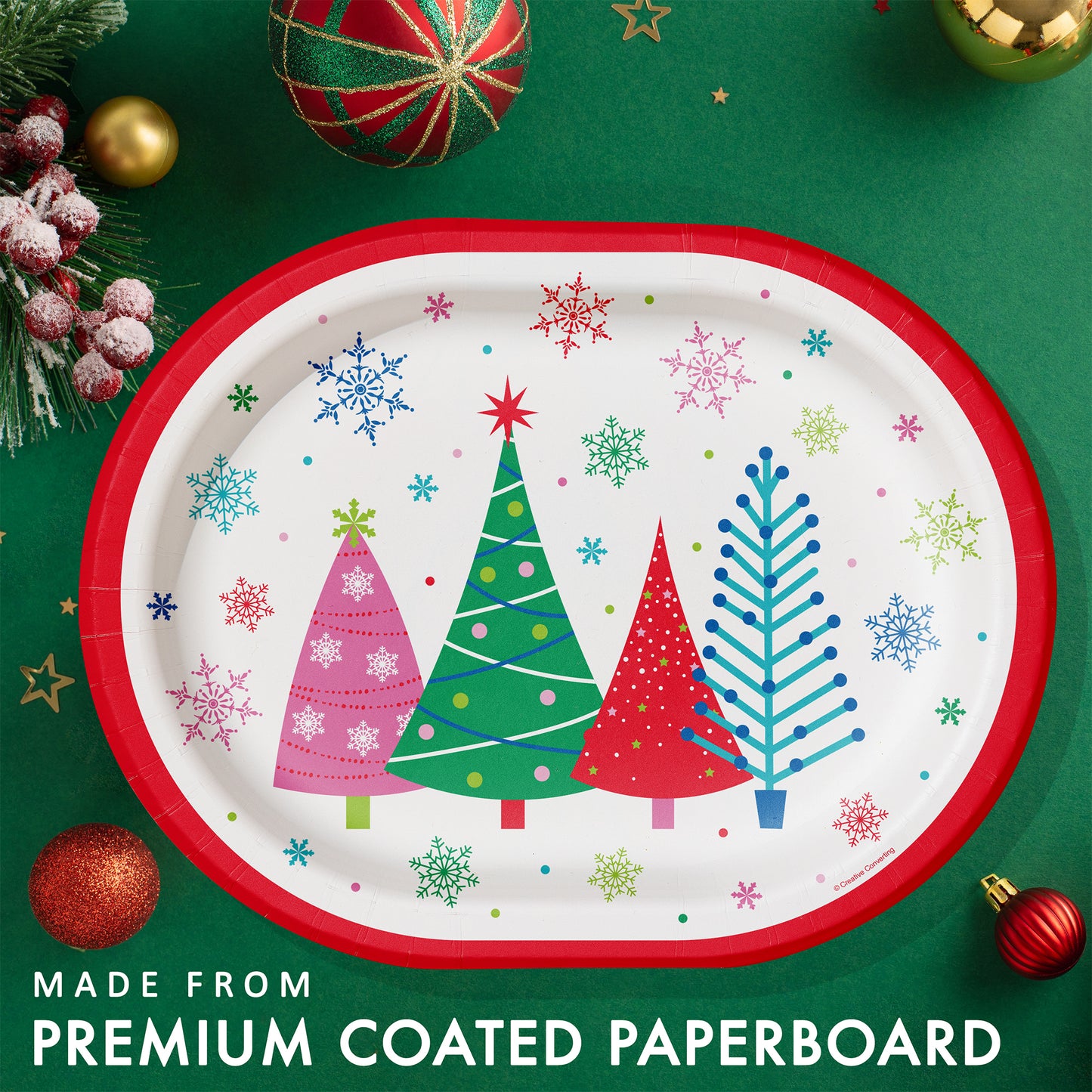 Joyful and Jolly Oval Dinner Paper Plates 96 ct. Christmas-themed paper plate with trees and snowflakes on a green background with festive decorations.