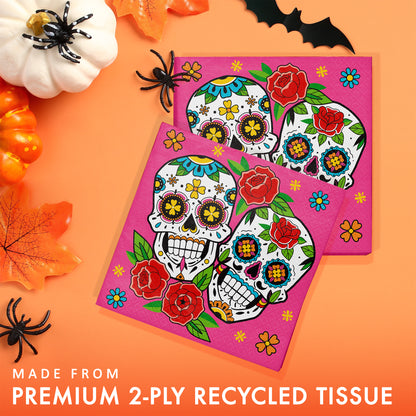 Skelebration Luncheon Napkins 192 ct. Colorful sugar skull design on pink tissue paper with Halloween decorations on an orange background.