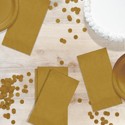 Gold paper plates and napkins with scattered gold confetti on a wooden surface