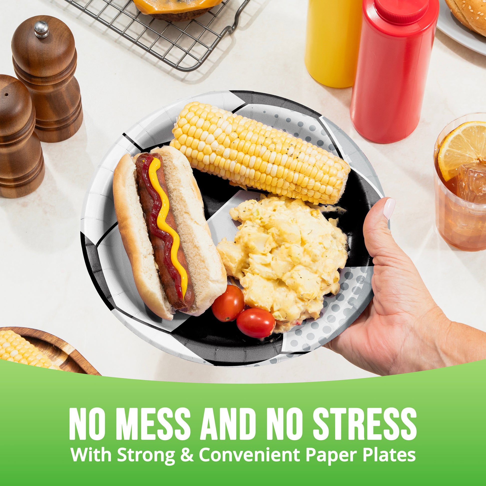 Hand holding a paper plate with a hot dog, corn on the cob, and potatoes, with text 'No Mess and No Stress'.