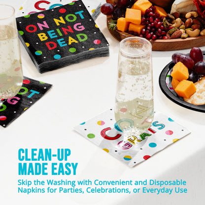 Disposable napkins with colorful text and a glass of water on a table with snacks.