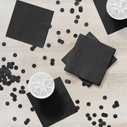 Black napkins and confetti on a light wooden surface