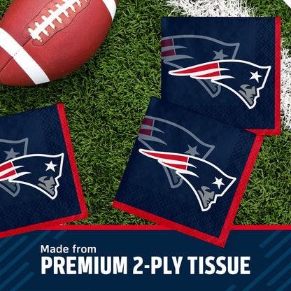 Three navy blue New England Patriots themed square tissue napkins with red borders and the Patriots logo, arranged on green turf next to a football, with a text banner at the bottom reading 'Made from PREMIUM 2-PLY TISSUE'.