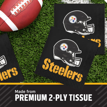 Black Pittsburgh Steelers themed square napkins with a helmet logo and yellow 'Steelers' text, arranged on green turf with a football prop and a banner reading 'Made from PREMIUM 2-PLY TISSUE'.