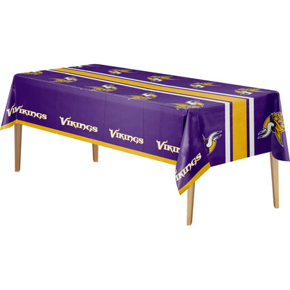 A purple Minnesota Vikings themed rectangular tablecloth with gold and white stripes, team logos, and the word 'Vikings' printed repeatedly, shown on a white background with wooden table legs visible.