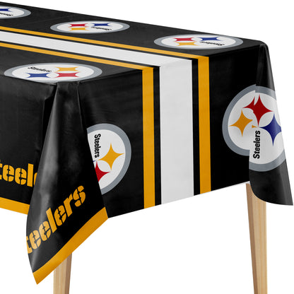 A Pittsburgh Steelers themed tablecloth draped over a table on wooden legs, featuring the team's circular logo and 'Steelers' text on a black background with yellow, white, and gray stripes.