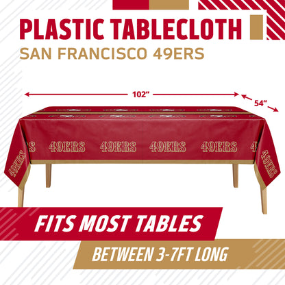 San Francisco 49ers themed plastic tablecloth shown on a table with dimension arrows indicating 102 inches by 54 inches. The tablecloth is dark red with gold lettering and team graphics.