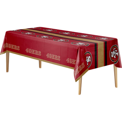 A rectangular table covered with a red, gold, and black San Francisco 49ers themed tablecloth, shown on a plain white background.