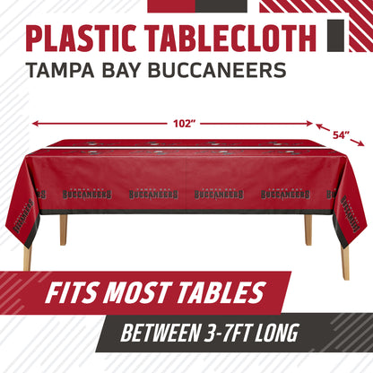 A red plastic tablecloth with Tampa Bay Buccaneers team graphics, shown on a table with dimension arrows indicating 102 inches by 54 inches. Text at the top reads 'PLASTIC TABLECLOTH TAMPA BAY BUCCANEERS' and a banner at the bottom says 'FITS MOST TABLES BETWEEN 3-7FT LONG'.