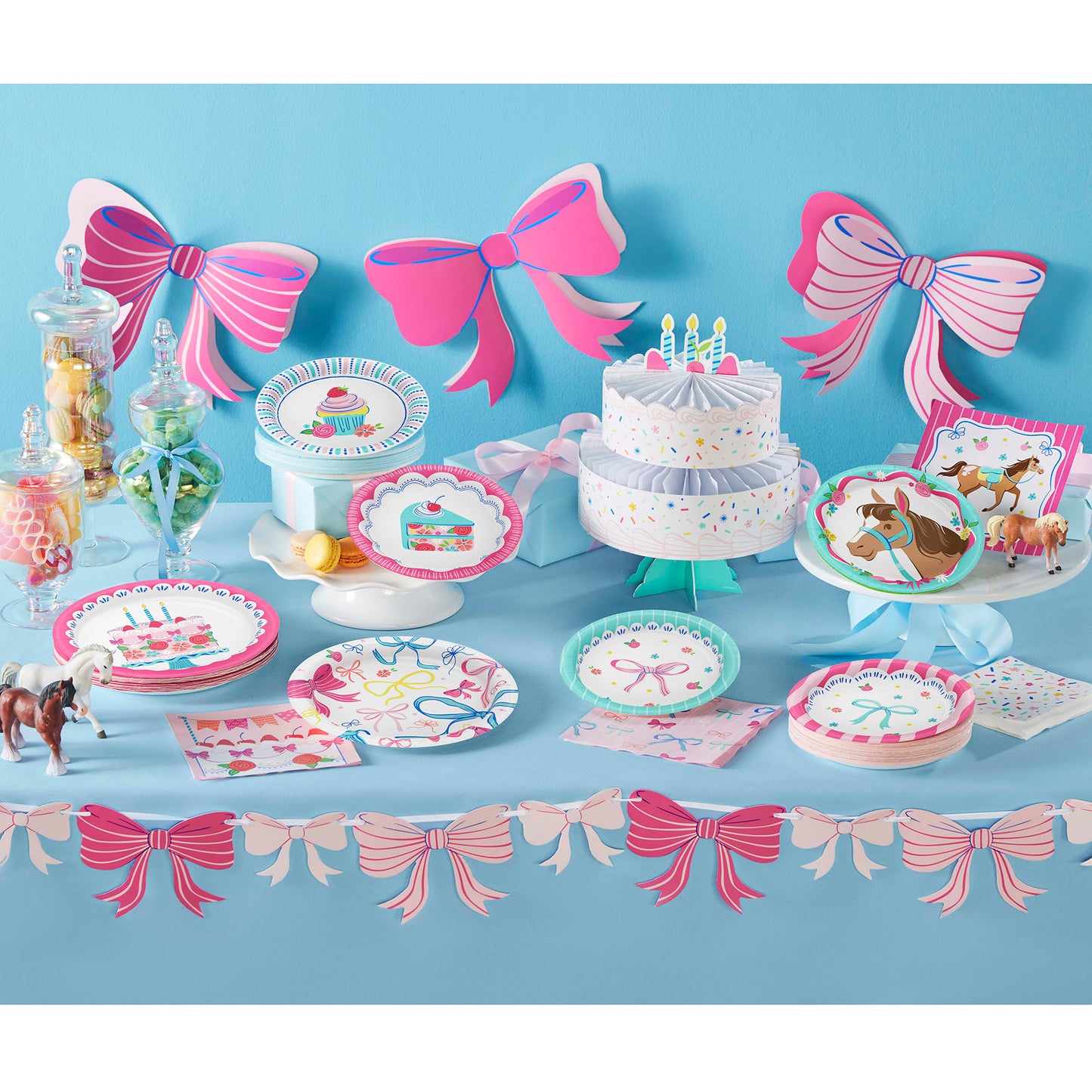 Birthday party setup with cake, plates, and decorations on a blue background