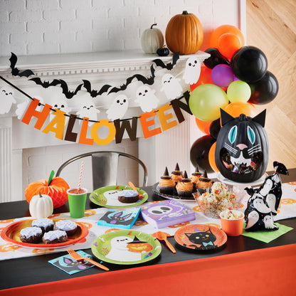 Happy Halloween Decorative Banners 12 ct. Halloween-themed table setting with decorations, including a 'HALLOWEEN' banner and pumpkins.