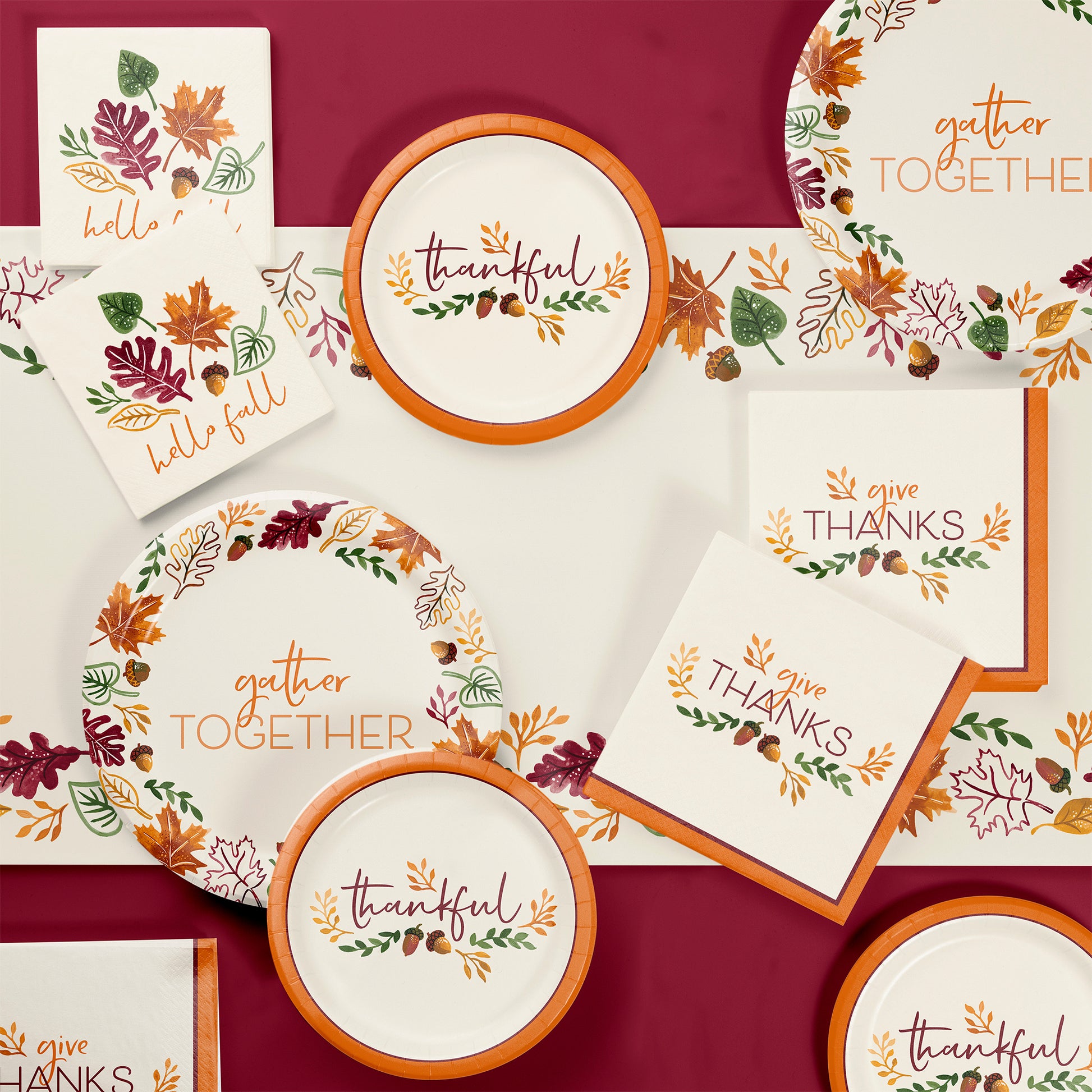 Fall Festivities Thanksgiving Paper Tablecloths 12 ct. Thanksgiving-themed tableware set with plates and napkins on a red background.