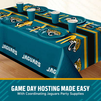 A Jacksonville Jaguars themed party table setting featuring a teal, black, and gold printed tablecloth, matching plates, cups, and utensils, displayed on a wooden floor with a promotional banner at the bottom.