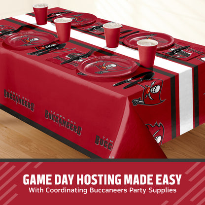 Tampa Bay Buccaneers themed party table setting with a printed tablecloth, matching plates, cups, and utensils, shown on a table with a promotional banner at the bottom that says "Game Day Hosting Made Easy".