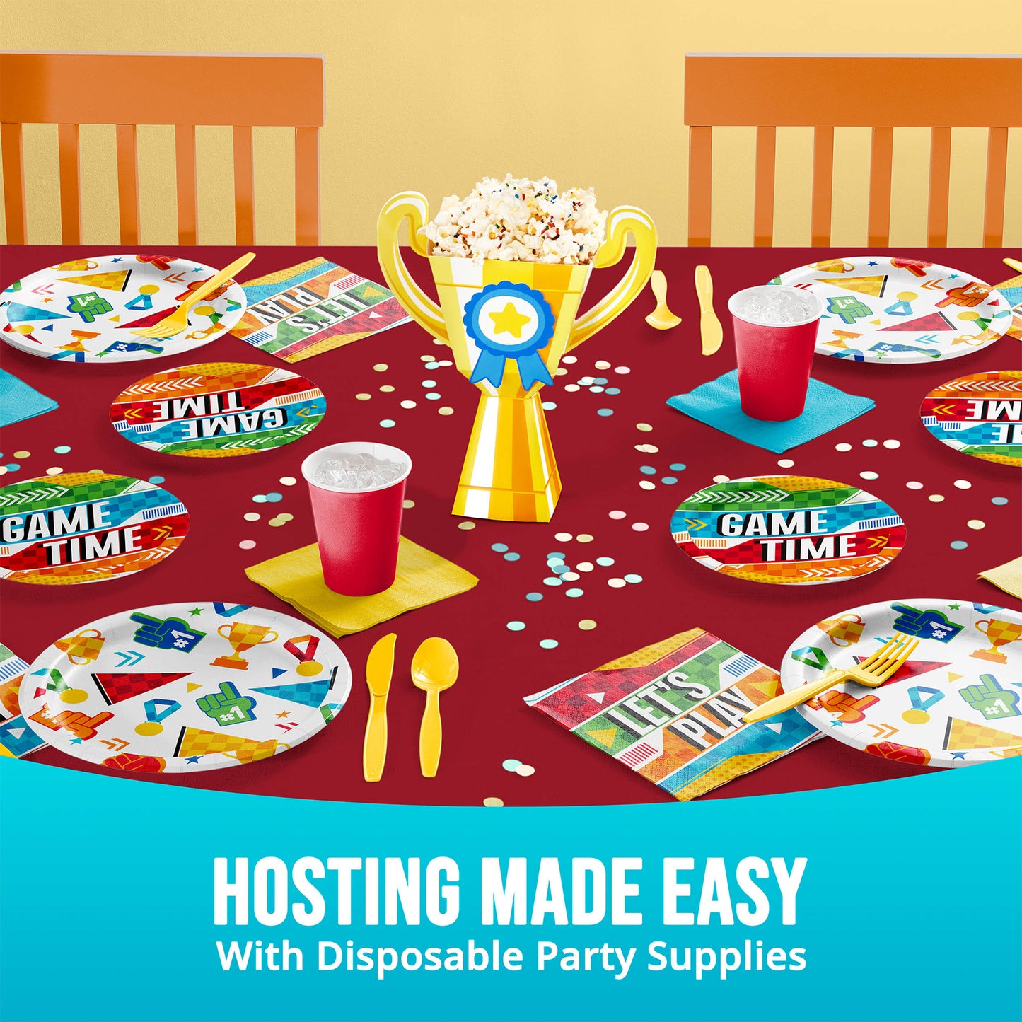 Disposable party supplies on a table with 'Game Time' plates, cups, and a trophy.