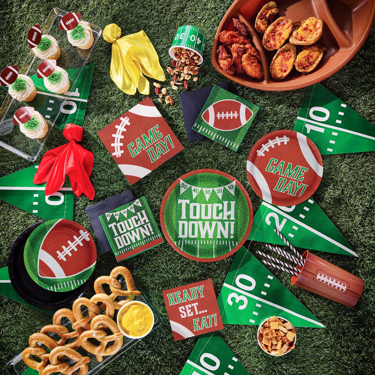 Football Drink Holder 12 ct. Game day-themed tableware, snacks and decorations on a grass-like surface